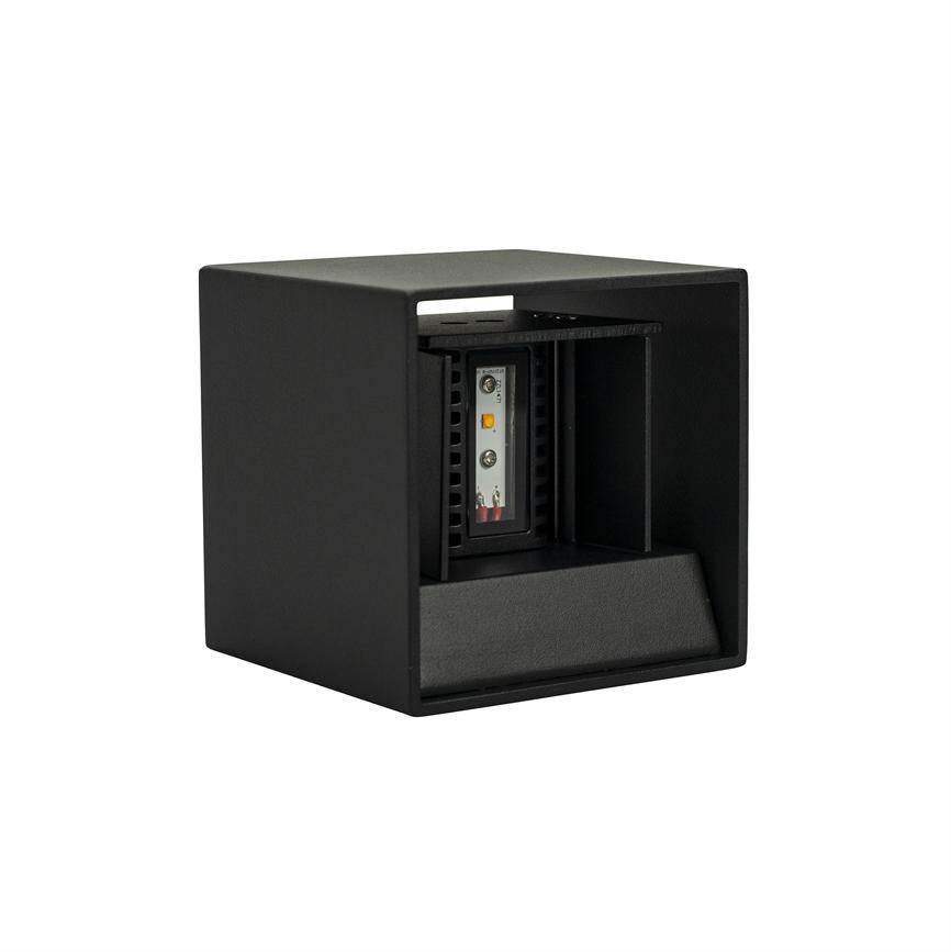 Die schwarze kubische Leuchte zeigt ein internes LED-Modul. Das Modul sitzt hinter einer offenen, nach vorne/unten gerichteten Frontplatte mit mattem Finish und räumlicher Aussparung, dargestellt auf weißem Hintergrund.