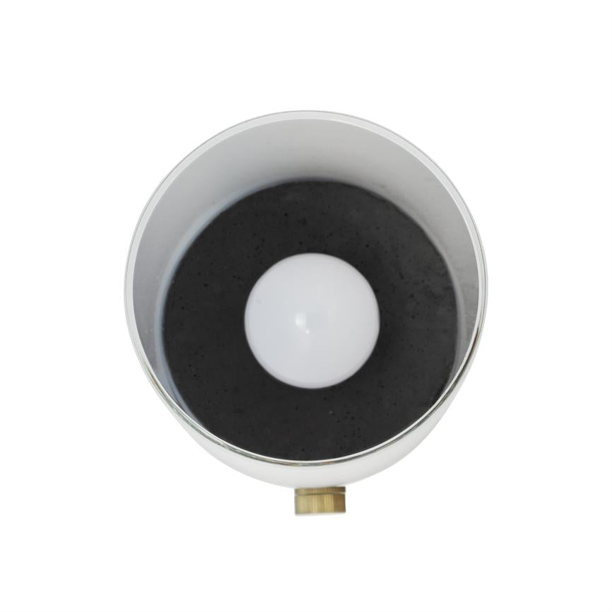 Eine weiße Lichtquelle (Glühbirne) ist in einem kreisförmigen, silberfarbenen Metallschirm mit dunkler Innenseite zentriert; Unten ist vor einem weißen Hintergrund ein kleiner Messingknopf zu sehen.