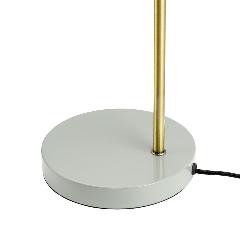Der runde Metallsockel trägt einen schlanken Messingstab; seitlich ist eine mit schwarzem Stoff umwickelte Kordel herausgeführt. Das Objekt steht vor einem neutralweißen Hintergrund.