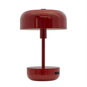 Die rote Tischlampe steht zentral mit einem runden Schirm über einem schlanken Pfosten und einem runden Fuß mit schwarzem Ein-/Aus-Knopf; minimalistisches Design auf neutralweißem Hintergrund.