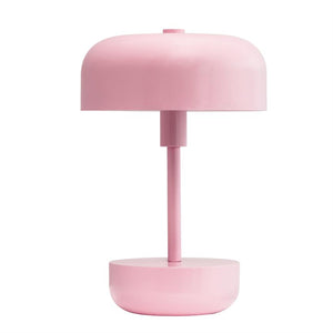 Tischleuchte steht vertikal; hat einen zylindrischen Stiel, einen abgerundeten Schirm und einen schalenförmigen Sockel in einfarbigem Rosa; vor einem neutralweißen Hintergrund platziert.