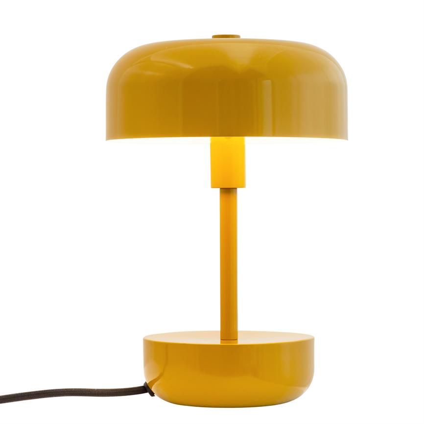 Gelbe Tischleuchte mit kuppelförmigem Schirm, vertikalem Schaft und rundem Sockel; Die Lampe ist eingeschaltet, wirft Licht nach unten und hat ein sichtbares schwarzes Kabel vor einem weißen Studiohintergrund.