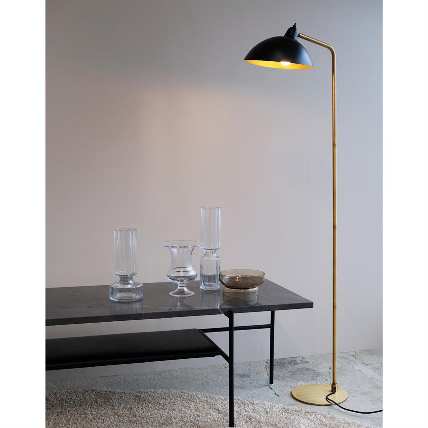 Stehleuchte mit schwarzem Schirm und goldenem Schaft wirft warmes Licht auf einen dunklen Marmortisch mit vier Glasvasen; Ich bin ein minimalistischer Rum mit viel Liebe, Beton und klarem Papier.