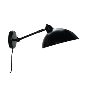 Sort metalvæglampe med udstrakt, ledbar arm, der holder en stor halvkugleformet skærm pegende nedad; kablet hænger løst mod en ensartet hvid baggrund.