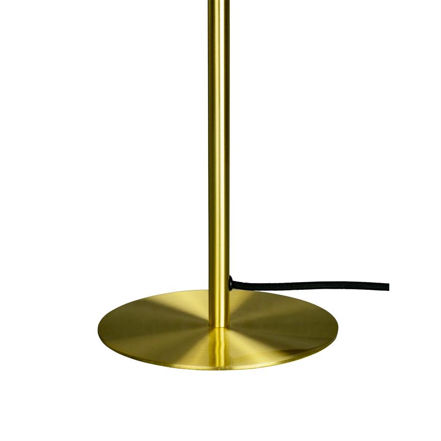 Messingfarbener Lampensockel mit schlankem Stab ruht auf einem flachen, runden Sockel; Auf weißem Grund verläuft eine schwarze Textilschnur von der Stange nach rechts.