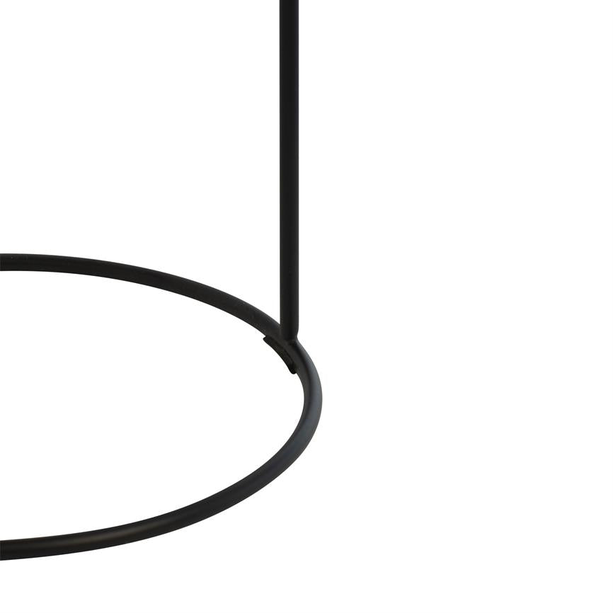 Sort metalring (bund) forbinder til en lodret, tynd stang via en svejset forbindelse; fungerer som et simpelt møbel- eller lampestativ mod en hvid baggrund.