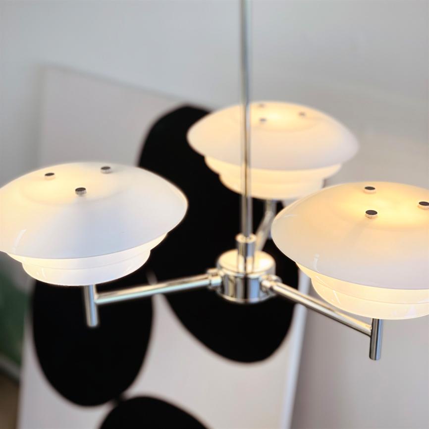 Eine moderne Deckenleuchte hängt und strahlt warmes, diffuses Licht aus; Im Hintergrund hängt ein abstraktes Schwarz-Weiß-Gemälde an der Wand.