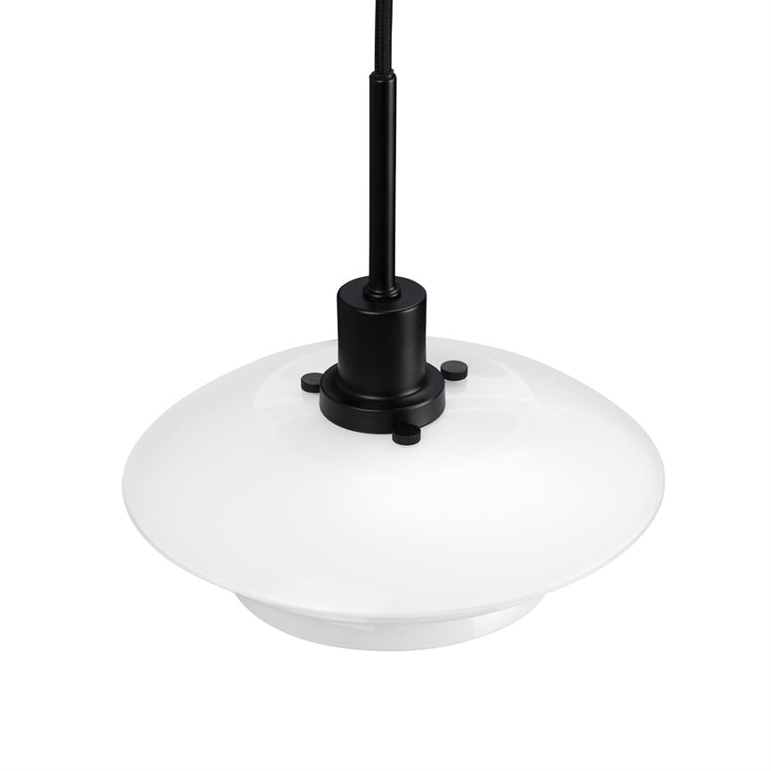 Hvid rund pendel-lampe hænger i et sort stofbeklædt kabel; sort metalfatning fastgør glaskuppen med tre små skruer, mod en ensartet hvid baggrund.