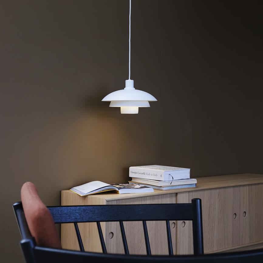 Weiß pendel Die Lampe hängt und wirft sanftes Licht über ein helles Holz-Sideboard mit aufgeschlagenen und gestapelten Büchern, vor einer dunklen Wand und einem schwarzen Stuhl im Vordergrund. 
 Text auf dem Rücken: „Giorgio Locatelli Made in Italy“