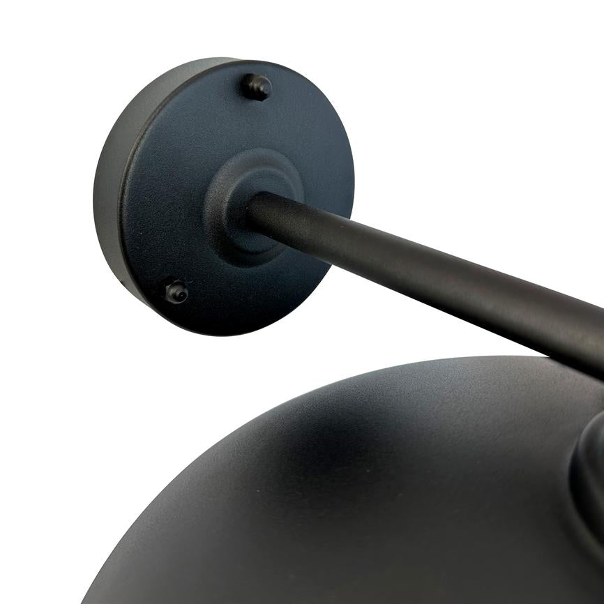 Wandleuchte aus mattschwarzem Metall: runde Wandhalterung und Arm, die sich diagonal zu einem gewölbten Schirm erstrecken; Nahes Detail auf weißem, neutralem Hintergrund.