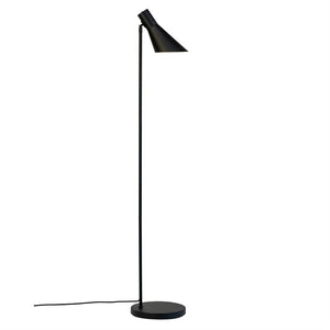Sort gulvlampe står og kaster lys nedad med en vinklet, konisk skærm; slank stang, rund fod og synlig ledning på hvid baggrund.