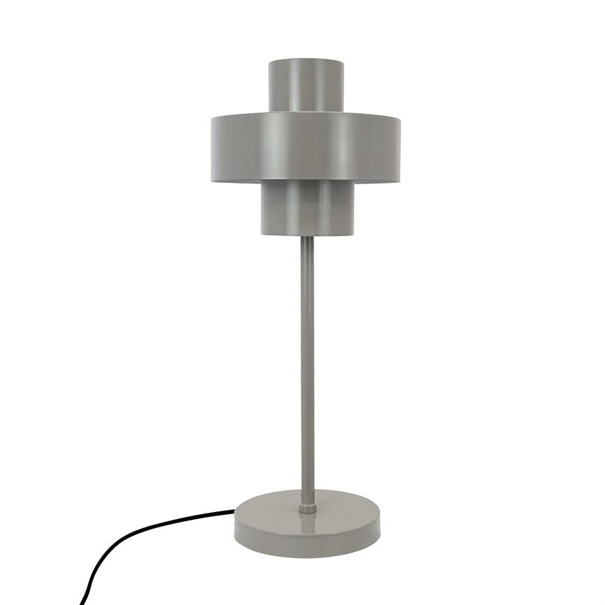Grå bordlampe står lodret på en rund fod; tynd central stang bærer lagdelt cylindrisk skærm; mat metalfinish; sort ledning ligger bøjet til venstre på hvid baggrund.