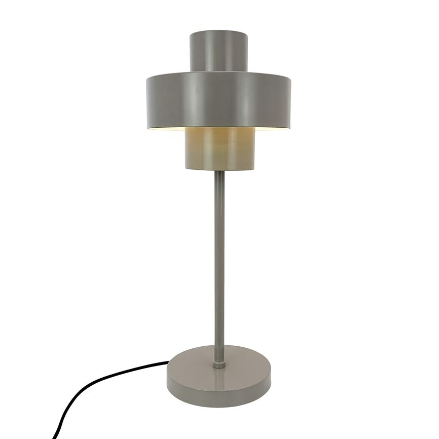 Bordlampe med grå, lagdelt cylindrisk skærm lyser svagt nedad; slank stang og rundt fodstykke, sort ledning løber ud, står foran en neutral hvid baggrund.
