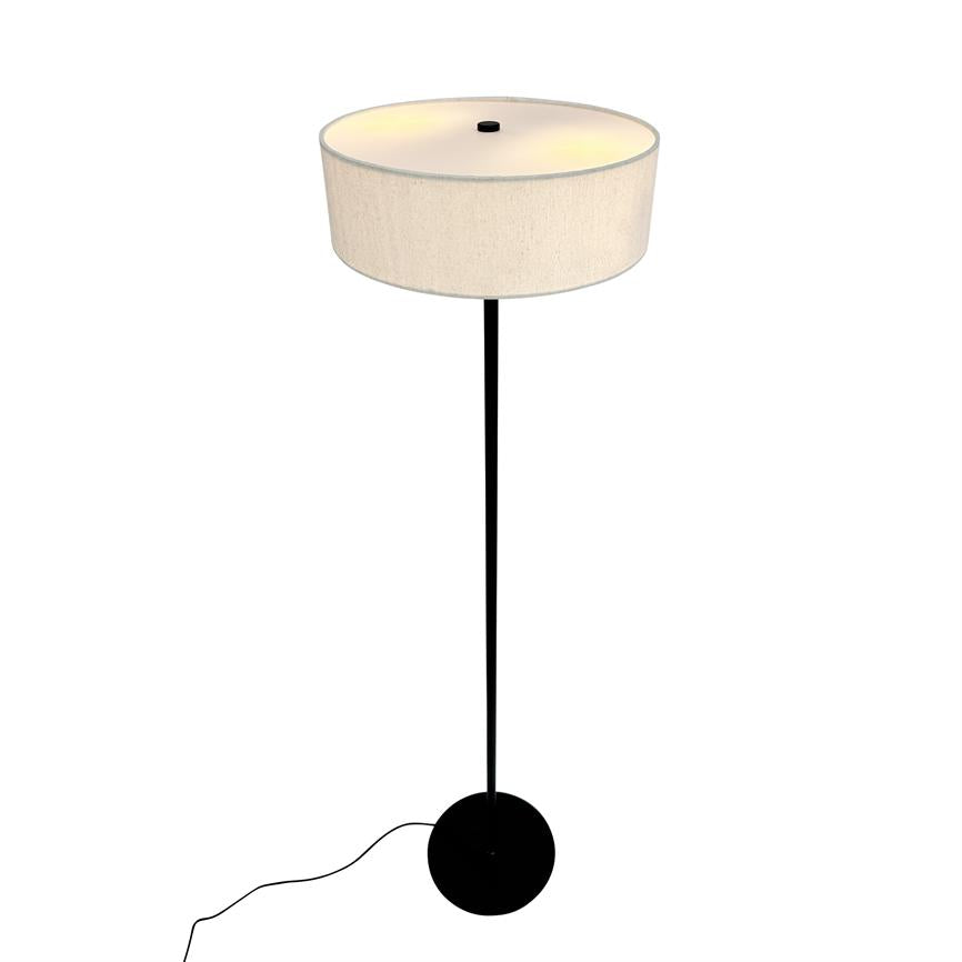 Eine Stehlampe strahlt weiches, warmes Licht auf einem schlichten weißen Hintergrund aus; Sie hat einen hohen, schlanken schwarzen Stab, einen runden schwarzen Fuß und einen großen beigen zylindrischen Lampenschirm.