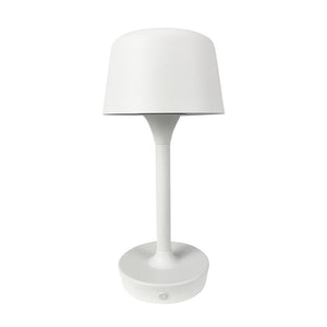 Hvid bordlampe står oprejst; tætsiddende lampskærm, slank stang og rund fod med trykknap, fotograferet mod ensartet hvid baggrund.