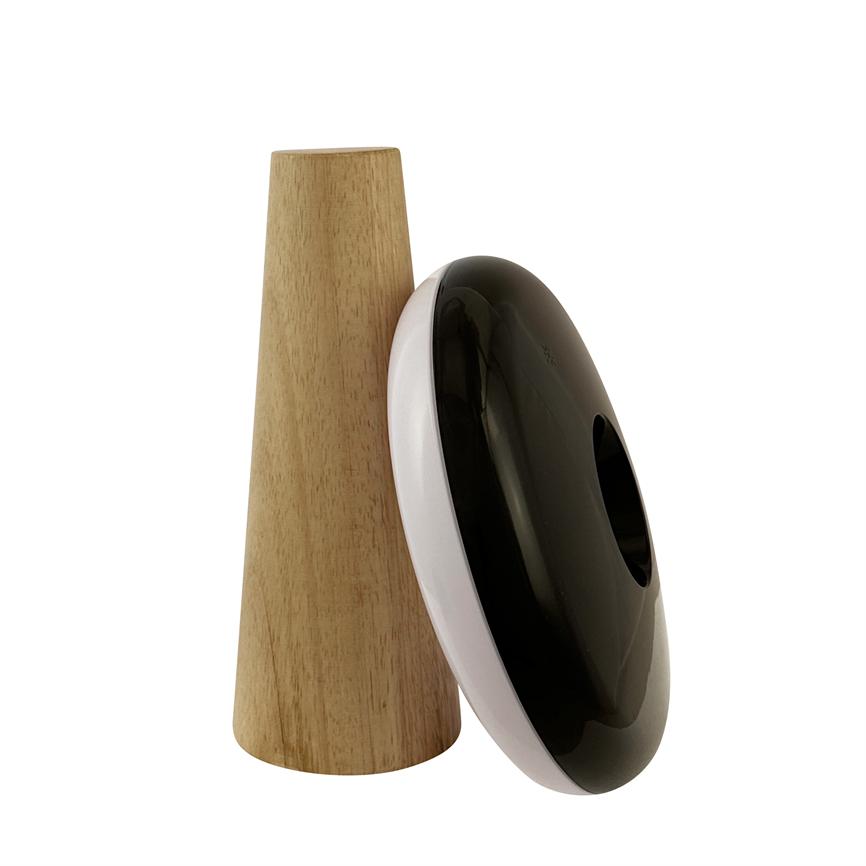 Schwarz-weißes, donutförmiges Gerät mit glänzend schwarzer Front lehnt an einem aufrechten, kegelförmigen Holzträger; beide stehen auf einem einheitlichen weißen Hintergrund in einem Produktfoto.