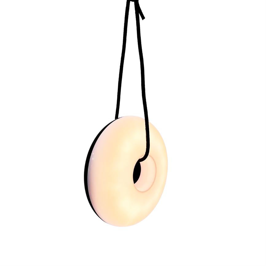 Der glasierte Donut in hellen Pastelltönen hängt an einer schwarzen Schnur, die von oben herabgelassen wird, und schwebt vor einem einfarbigen weißen Hintergrund.