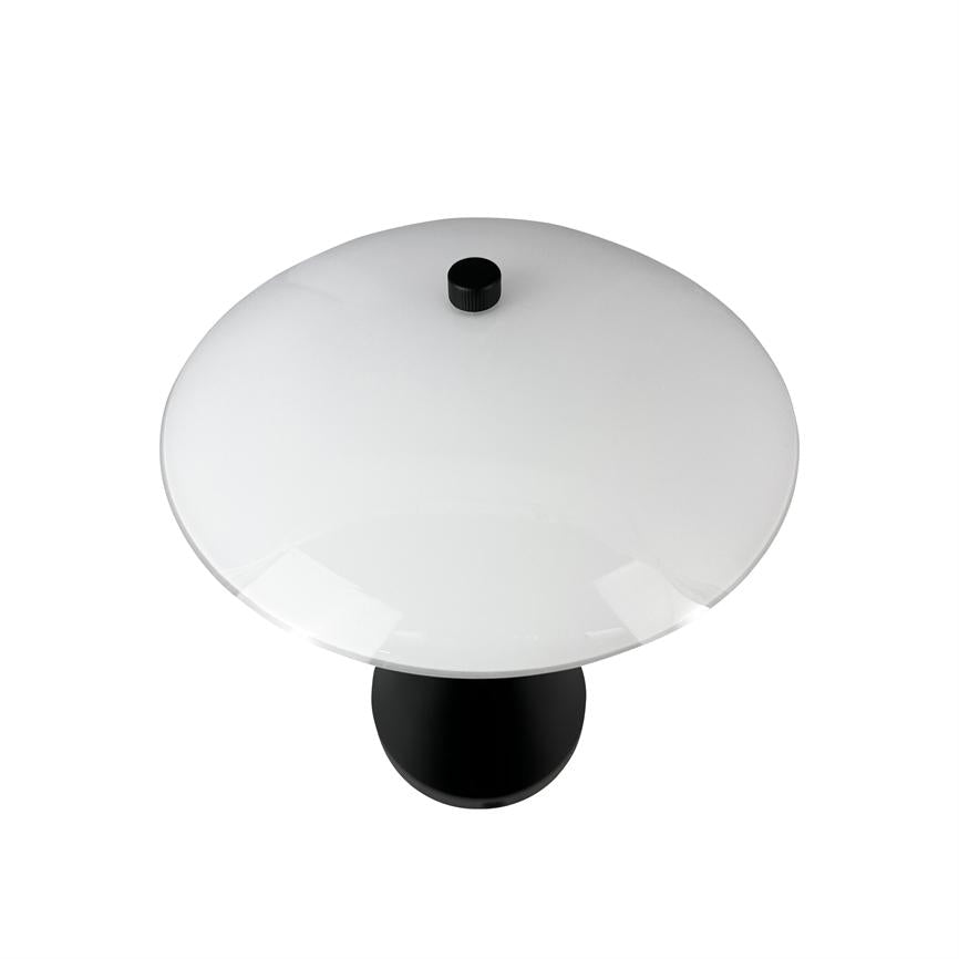 Tischlampe steht allein auf weißem Hintergrund; Es hat eine große runde weiße Kuppel mit einem schwarzen Knopf oben und einem schwarzen zylindrischen Fuß, von oben gesehen.