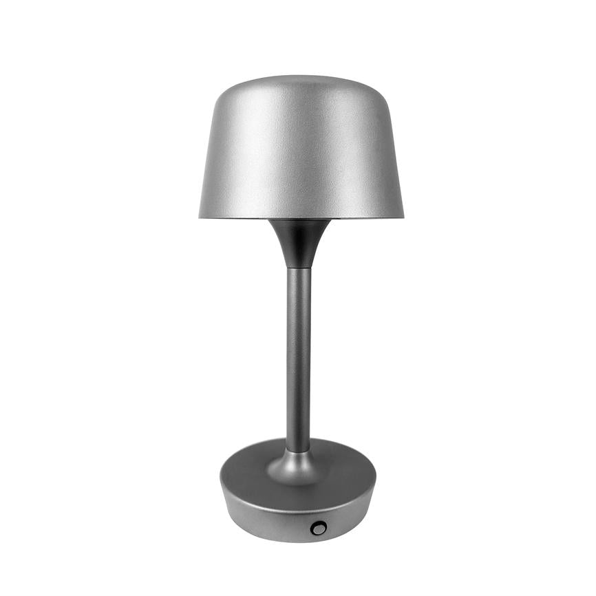 Sølvgrå bordlampe står slukket på en rund fod, med slank midterstang og afrundet skærm; minimalistisk moderne design med lille trykknap på basen, mod en hvid baggrund.