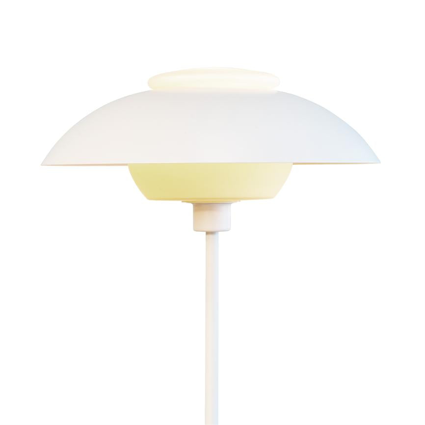 Die weiße Lampe mit rundem Schirm strahlt weiches, warmes und diffuses Licht auf einem dünnen weißen Ständer mit geschichtetem, minimalistischem Schirm vor einem neutralweißen Hintergrund aus.
