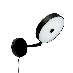 Runde Wandleuchte mit schwarzem Metallrahmen und weißem Diffusor; Auf einem kurzen Arm aus einer runden Wandplatte nach außen geneigt, mit sichtbarem schwarzem Draht, vor neutralweißem Hintergrund.