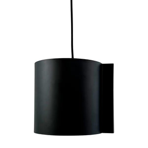 En sort, cylindrisk lampe hænger i en tynd ledning mod en hvid baggrund; en flad rektangulær monteringsplade er synlig ved siden af cylinderen.