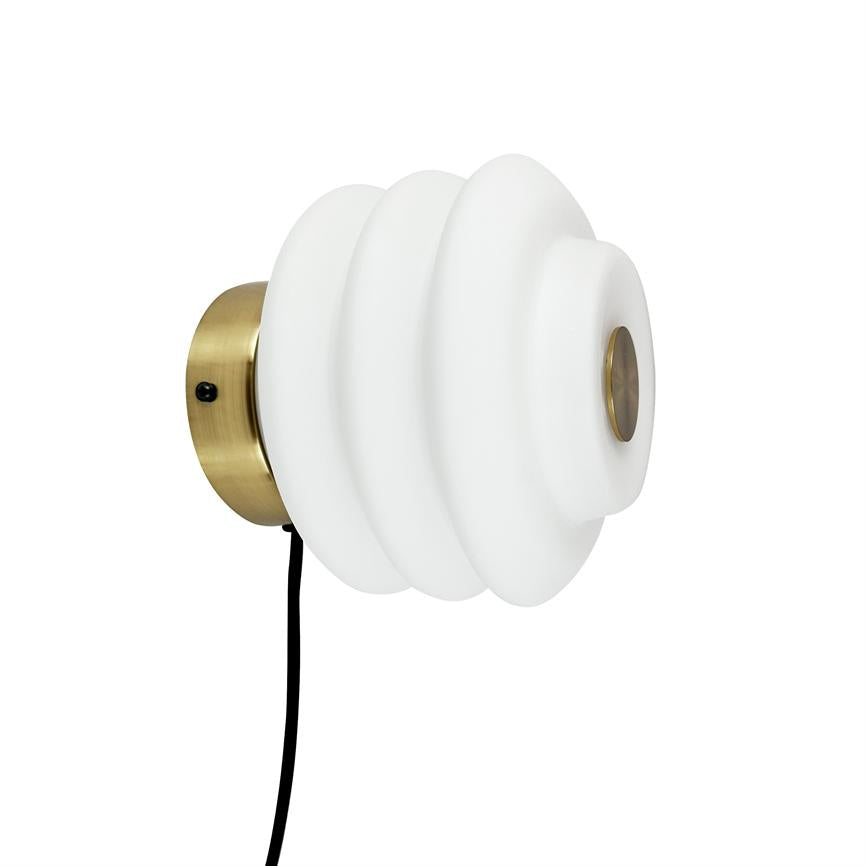 Væglampe med hvid, ribbet glaskuppel monteret på en rund messingvægplade; et sort kabel hænger ned fra beslagets underside; præsenteret mod en neutral, hvid baggrund.