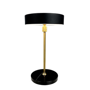 Tischlampe mit schwarzem zylindrischem Schirm, schlankem goldfarbenem Stab und rundem schwarzem Marmorsockel; Aufrecht stehend auf weißem Hintergrund, funktional und elegant.