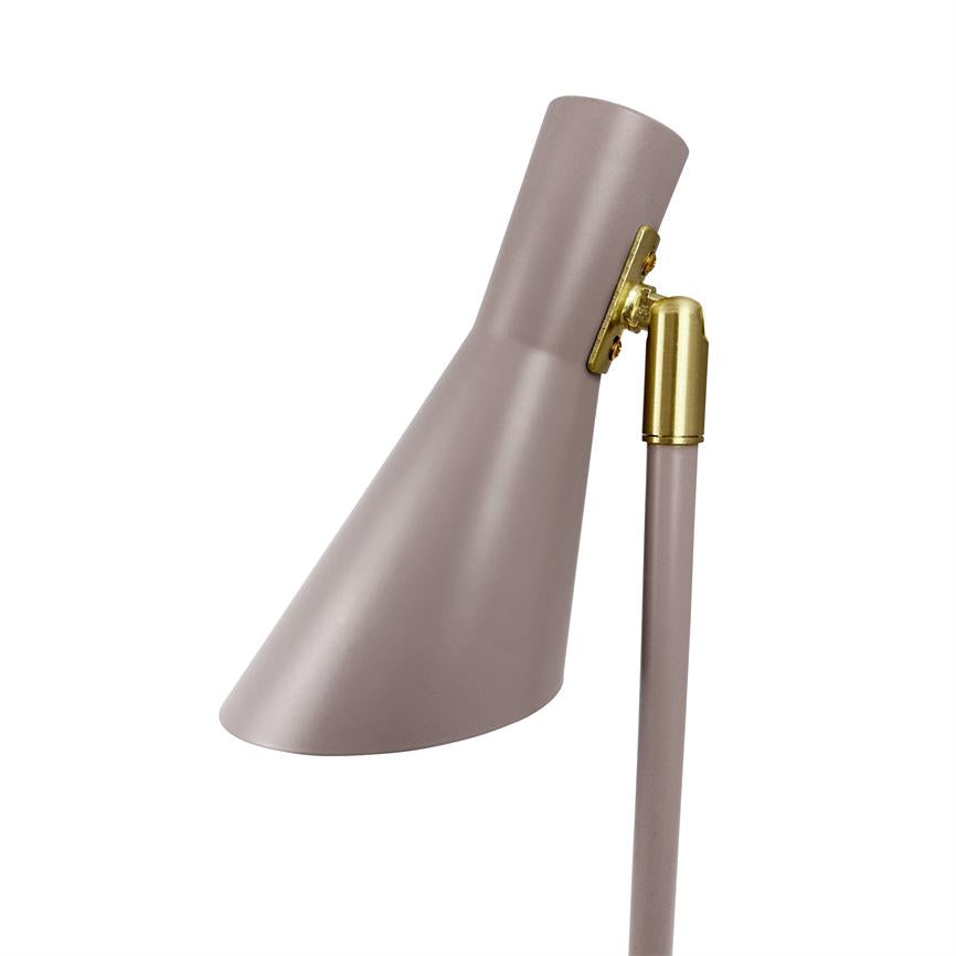 Ein staubrosa Lampenkopf neigt sich nach links unten; Es ist mit einem schlanken Stab mit einem goldenen Messingglied verbunden und wird isoliert vor einem weißen Hintergrund dargestellt.