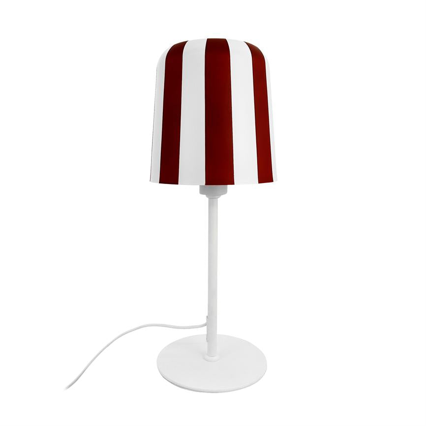 Bordlampe står oprejst; lampeskærm med brede, lodrette røde og hvide striber; tynd hvid stander og rund base; hvid ledning slanger let ud mod venstre på ensartet hvid baggrund.