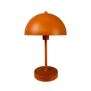 Orange bordlampe står stille; halvkugleformet skærm over slank central stang og rund base med synlig tændknap, placeret mod ensartet hvid baggrund.