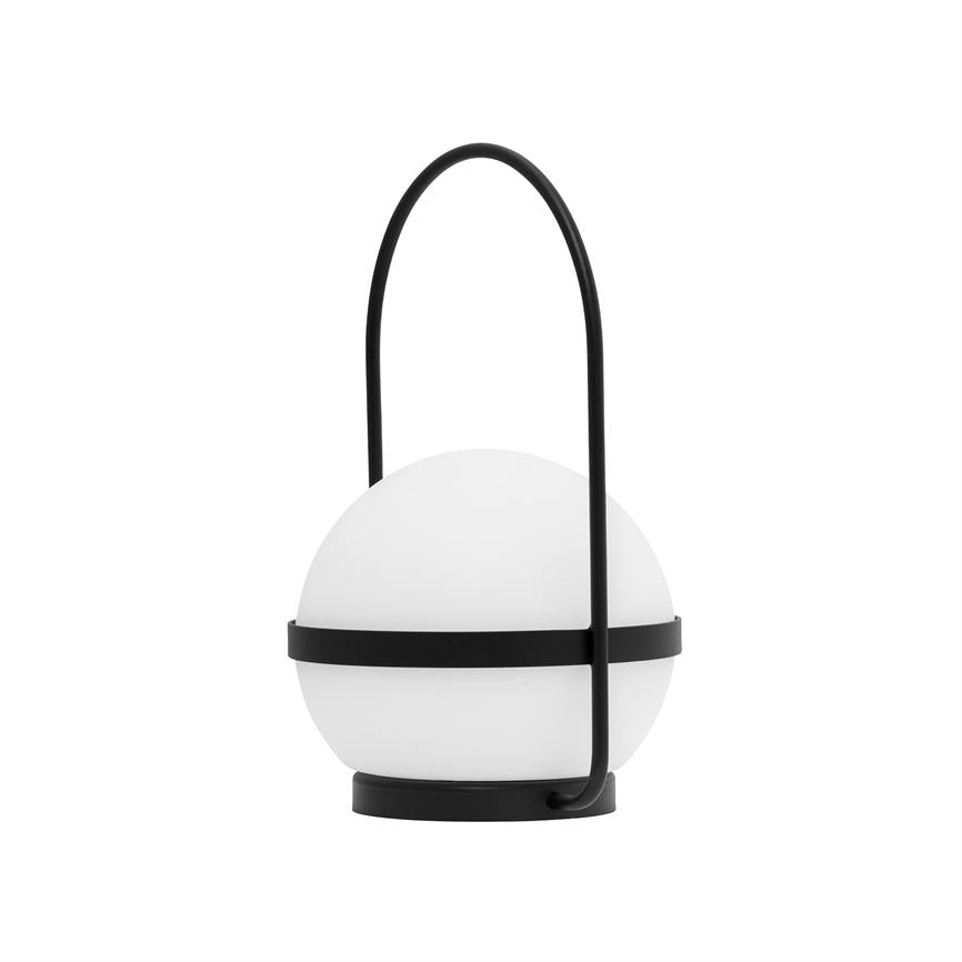 Tischleuchte mit weißem Kugelschirm, eingerahmt von schwarzen Metallbändern und geschwungenem schwarzem Griffbügel; es ruht auf einem kleinen runden schwarzen Fuß vor weißem Hintergrund.