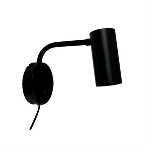 Schwarze Wandleuchte aus Metall montiert auf runder Wandplatte, Arm nach außen gebogen und zylinderförmiger Leuchtenkopf schräg nach unten gerichtet; schlichtes, modernes Design vor weißem Hintergrund.