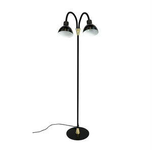Eine schwarze Stehlampe mit zwei gebogenen Schirmen; die Arme beugen sich nach außen und zeigen leicht nach unten; steht auf einem runden schwarzen Sockel mit Messingdetails und sichtbarem schwarzem Draht vor weißem Hintergrund.