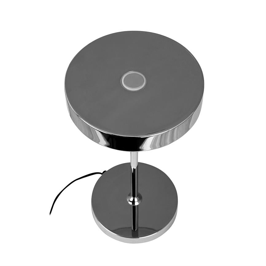 Tischlampe aus Chrom mit runder Oberseite und zentraler Touch-Taste; steht auf einer schlanken Säule über einem runden Fuß, Kordel läuft vor weißem, neutralem Hintergrund aus.