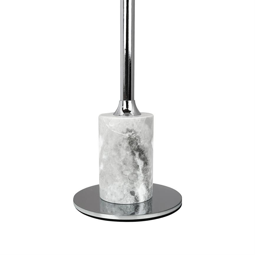 Die Toilettenbürste mit verchromtem Griff steht aufrecht in einem zylindrischen, weißgrauen, mit Marmor und Metall verkleideten Halter, platziert auf einem runden, hochglanzpolierten Sockel, isoliert vor einem einheitlichen weißen Hintergrund.