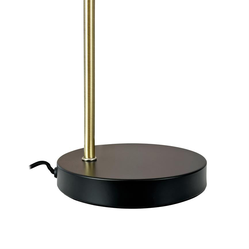 Der runde schwarze Sockel der Lampe trägt einen vertikalen, dünnen Messingstab; Auf weißem Hintergrund ragt nach links ein schwarzes Netzkabel heraus.