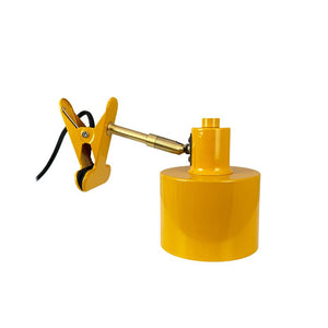 Klemmlampe mit Metallarmklemmen über schwarzem Kabel und gummierten Backen, trägt einen zylindrischen gelben Lampensockel; Produktfoto auf einem einheitlichen weißen Hintergrund.