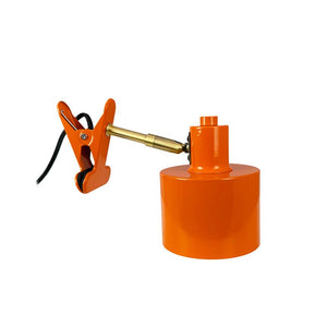 Mit der Klemme wird ein verstellbarer Messingarm an einem orangefarbenen zylindrischen Lampensockel mit schwarzem Kabel auf weißem Hintergrund befestigt.