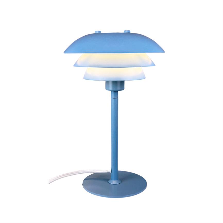 Die Tischlampe strahlt weiches, warmes Licht durch drei geschichtete Schirme aus, die auf einem schlanken blauen Stab und einem runden Sockel montiert und vor einem neutralweißen Hintergrund platziert sind.